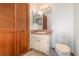 Bathroom with tile floors, wood-themed cabinet storage, toilet, sink, and triple mirror at 1007 Glendale St, Orlando, FL 32807