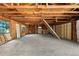 Spacious unfinished basement, featuring exposed wooden beams and concrete flooring, awaits transformation into a personalized area at 11540 Harbor Rd, Leesburg, FL 34788