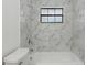 Modern bathroom with marble-style tiled walls, a bathtub, and a shower, illuminated by a window at 11540 Harbor Rd, Leesburg, FL 34788