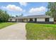 Inviting home exterior with well-maintained lawn and concrete driveway leading to covered parking area at 11540 Harbor Rd, Leesburg, FL 34788