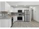 Modern kitchen features stainless steel appliances, gray brick backsplash, white cabinets, and granite countertops at 11540 Harbor Rd, Leesburg, FL 34788
