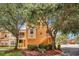 Three-story townhome with stairs leading to the second level, lush landscaping, and blue sky at 12414 Baleria Cv # 104, Orlando, FL 32837