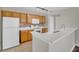 Bright kitchen with wood cabinets, white appliances, and breakfast bar at 12414 Baleria Cv # 104, Orlando, FL 32837