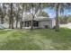 Wide view of backyard with screened-in porch, lush lawn, privacy fence and mature trees at 1307 Pup Fish Ln, Deland, FL 32724