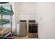A modern laundry room with a washer, dryer and metal storage shelving at 13208 Leggett Aly, Orlando, FL 32827