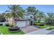 Charming two-story home featuring a manicured lawn, palm trees, and a brick driveway leading to a three-car garage at 1938 Filly Trl, Oviedo, FL 32765