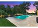 Backyard swimming pool with a travertine deck, spa, and plenty of space for relaxation at dusk at 1938 Filly Trl, Oviedo, FL 32765