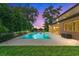 Beautiful backyard swimming pool with a travertine deck, screened lanai, and well-maintained landscaping at dusk at 1938 Filly Trl, Oviedo, FL 32765