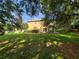 Green backyard with a covered patio, showcasing the home's outdoor space and mature trees at 2020 Rushden Dr, Ocoee, FL 34761