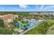 An aerial view of a community pool, waterslide, and lush landscaping, nestled amongst mature trees and gardens at 2531 Maneshaw Ln, Kissimmee, FL 34747