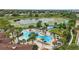 Aerial view showcasing the pool with sunbathers, lush greenery and landscaping, along with waterslides at 2531 Maneshaw Ln, Kissimmee, FL 34747