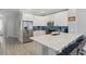 Modern kitchen featuring white cabinets, stainless steel appliances, a quartz countertop island with seating, and a blue tile backsplash at 2531 Maneshaw Ln, Kissimmee, FL 34747
