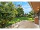 Lush backyard featuring a concrete patio, green lawn, privacy fence, and mature trees under a sunny sky at 2809 Gulf Winds Ct, Oviedo, FL 32765