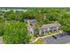 Aerial view of townhomes with parking area, tree coverage and a lake in the background on a bright sunny day at 2930 Candela Ct, Apopka, FL 32703