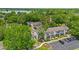 Aerial view of townhomes with parking area, tree coverage and a lake in the background on a bright sunny day at 2930 Candela Ct, Apopka, FL 32703
