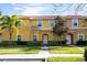 Charming townhome with vibrant yellow exterior, red tile roof, and well-manicured landscaping at 3065 Yellow Lantana Ln, Kissimmee, FL 34747