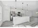 A bright, open kitchen featuring an island, stainless appliances, modern pendant lighting, and sleek white cabinetry at 3159 Sw 127Th Lane Rd, Ocala, FL 34473