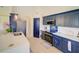 Bright kitchen boasts navy cabinets, quartz countertops, stainless appliances, and decorative tile backsplash at 456 Old Bridge Cir, Davenport, FL 33897