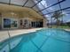 Sparkling pool with a screened-in lanai, outdoor seating, and a lush tropical backdrop at 456 Old Bridge Cir, Davenport, FL 33897