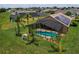 Aerial view of a home with a screened-in pool and solar panels in a neighborhood at 456 Old Bridge Cir, Davenport, FL 33897