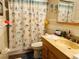 Well-lit bathroom featuring a shower with a seashell shower curtain and storage under the sink at 46 Carriage Hill Cir, Casselberry, FL 32707