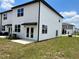 Rear view of a contemporary townhome with white siding, a small patio, and a well-manicured lawn at 477 Madison Dr, Davenport, FL 33837