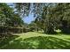 Lush backyard with mature trees, manicured lawn, and a glimpse of the screened pool area, offering a serene view at 492 Lanarkshire Pl, Apopka, FL 32712