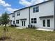 Exterior shot of a backyard featuring new construction townhomes, green grass, and a private patio area at 497 Madison Dr, Davenport, FL 33837