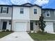 Two-story townhome featuring a one-car garage, nicely landscaped front yard, and neutral exterior paint at 497 Madison Dr, Davenport, FL 33837