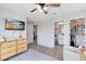 Bright bedroom with wood floors, ceiling fan, rattan dresser, TV, and access to bath and closet at 5677 Cedar Chase Dr, St Cloud, FL 34771