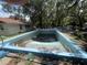 Backyard features a spacious, partially filled pool, needing maintenance, surrounded by lush trees at 578 3Rd St, Daytona Beach, FL 32117