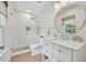 Bright bathroom featuring a glass enclosed shower with a rainfall showerhead, and a white vanity with a round mirror at 624 Richmond Street, Orlando, FL 32806