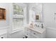 Bright bathroom with white vanity, a decorative mirror, and a large window at 6501 Matchett Rd, Belle Isle, FL 32809