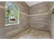 The tiled walk-in shower features a glass block window for natural light and privacy at 6720 Winter Garden Vineland Rd, Windermere, FL 34786