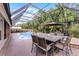 Outdoor dining and seating with a screened pool and lush green landscaping in the background at 806 Spring Island Way, Orlando, FL 32828