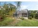 Spacious backyard with a screened-in pool enclosure, complemented by garden beds and lush landscaping at 985 N Lake Claire Cir, Oviedo, FL 32765
