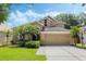 Charming two-story home featuring a two-car garage, manicured lawn, and lush landscaping under a bright blue sky at 985 N Lake Claire Cir, Oviedo, FL 32765