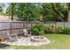 Charming backyard featuring a cozy fire pit, stone patio, wooden fence, and lush landscaping at 102 Sand Pine Cir, Sanford, FL 32773