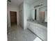 Bathroom features double sinks, white cabinets, and marble floors and countertops at 1754 35Th Nw St, Winter Haven, FL 33881