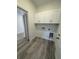 Bright laundry room with gray wood-look flooring, white cabinets, and washer/dryer hookups at 1754 35Th Nw St, Winter Haven, FL 33881