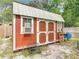 An outdoor, red-painted, storage shed features white trim, double doors and a window air conditioner, providing secure and cooled storage space at 219 E Fern Dr, Orange City, FL 32763