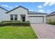 Charming single-story home with a well-manicured lawn, brick driveway, and a two-car garage at 2210 Romanum Dr, Winter Garden, FL 34787