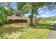 View of the brick home from the yard with a large tree providing ample shade at 236 Longhorn Dr, Apopka, FL 32712