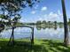 Picturesque lake view with a swing and swaying palm trees, providing a serene backdrop for relaxation and outdoor enjoyment at 2421 Queenswood Cir, Kissimmee, FL 34743