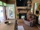 The rustic living room featuring a brick fireplace and views of the outdoor pool offers a cozy and inviting ambiance at 2648 Amsden Rd, Winter Park, FL 32792