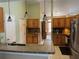Bright kitchen with granite countertops, wooden cabinetry, stainless steel appliances, tile backsplash, and hanging pendant lights at 2693 Maxwell W Ct, Kissimmee, FL 34743