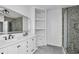 Bright bathroom featuring dual sinks, a stone tile shower and open shelving unit at 3030 Clubview Dr # Ge, Orlando, FL 32822