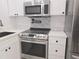 Modern kitchen featuring stainless steel stove, range hood, white cabinets, and quartz countertops at 3030 Clubview Dr # Ge, Orlando, FL 32822