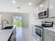 Well-lit kitchen featuring stainless steel appliances, gray cabinetry, and a view of the backyard through sliding glass doors at 3975 Silverstream Ter, Sanford, FL 32771