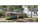 View of a single-story home featuring a covered parking area, landscaped lawn, and quaint curb appeal at 401 Sunny Ct, Fruitland Park, FL 34731